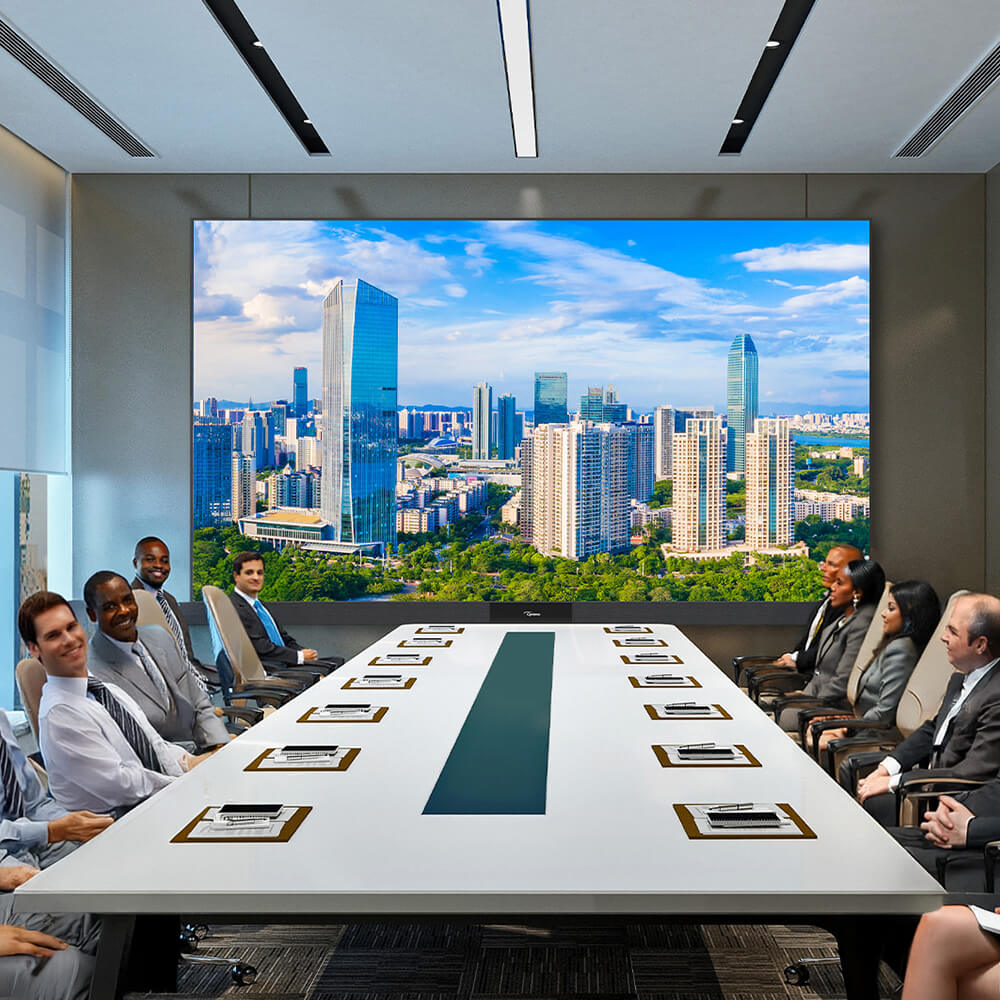 A board room with people having a business meeting in front of a large flat panel screen.